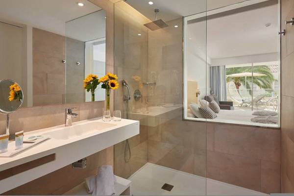 Girasol Hotel Badezimmer mit Glasdusche, Waschbecken und Sonnenblumen.