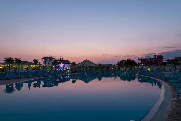 Sonnenuntergang am Pool des Sultan of Dreams Hotels mit blauen Liegen und Palmen