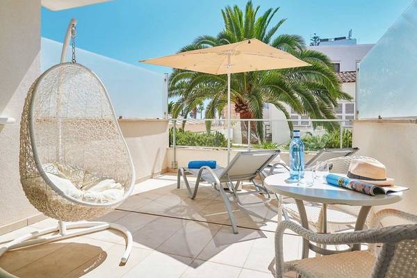 Hotelbalkon mit Hängesessel, Sonnenliegen und Sonnenschirm, Blick auf eine Palme.