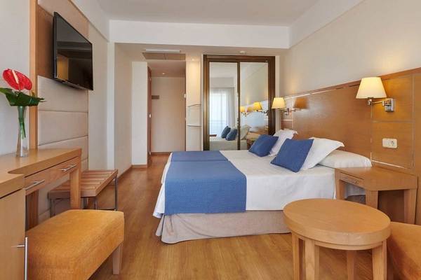 Ein modernes Hotelzimmer im Girasol Hotel mit zwei Betten, einem Fernseher und einer Tischlampe.