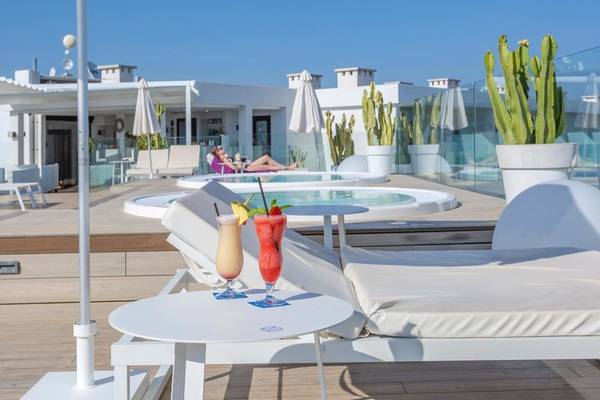 Außenbereich des Aparthotel Marins Playa mit Lounge-Stühlen, einem Tisch und einem Swimmingpool.