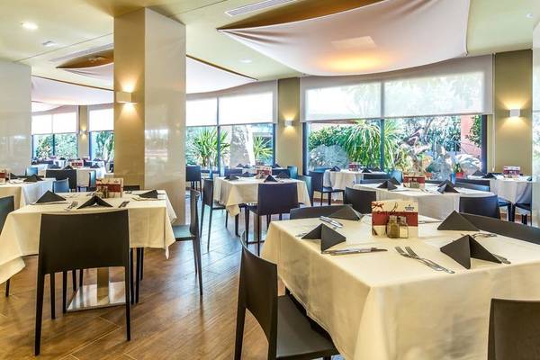 Innenansicht des Restaurants im Aparthotel Marins Playa mit gedeckten Tischen und Stühlen.