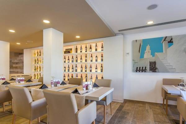 Innenbereich des Restaurants im Aparthotel Marins Playa mit gedeckten Tischen und einer Weinflaschenwand.