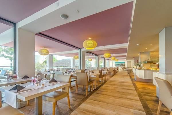 Innenansicht des Restaurants im Aparthotel Marins Playa mit Holzboden, runden Lampen und Tischdekoration.