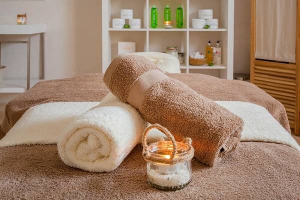 Wellnessbereich im Aparthotel Marins Playa mit einem Massagebett, Handtüchern und einem Kerzenglas.