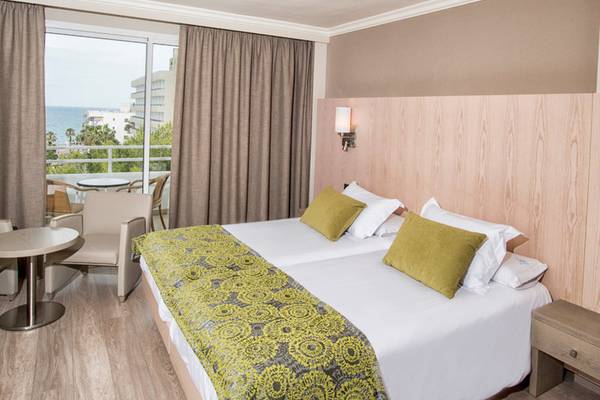 Zimmer im Aparthotel Marins Playa mit Meerblick, Doppelbett, Balkon und Tisch.