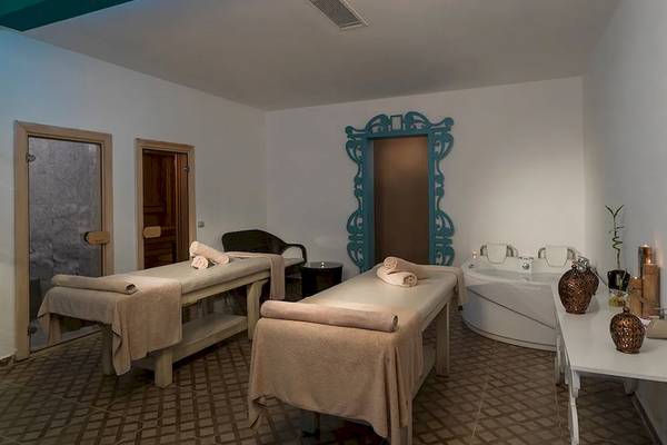 Spa-Behandlungszimmer im Sultan of Dreams Hotel mit zwei Massagetischen und einer Badewanne.