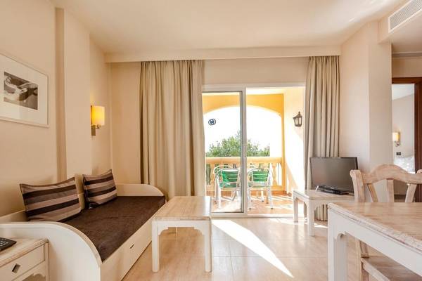Wohnbereich des Aparthotels Marins Playa mit einem Schlafsofa, Tisch und Fernseher.