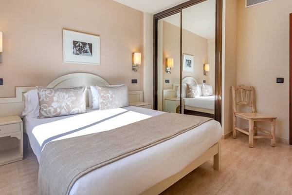 Ein Hotelzimmer im Aparthotel Marins Playa mit einem Doppelbett, Nachttischen und einem Spiegel.