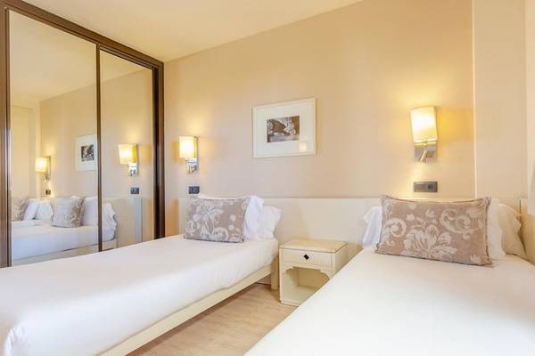 Doppelzimmer im Aparthotel Marins Playa mit zwei Betten, Nachttischen und Dekor.