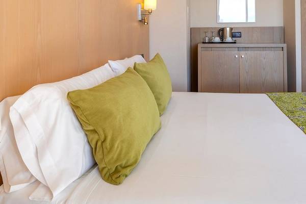 Hotelzimmer im Aparthotel Marins Playa mit grünen Kissen und einem Bett.