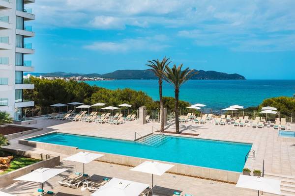 Außenbereich des Iberostar Cala Millor Hotels mit Pool und Sonnenliegen.