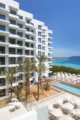 Außenbereich des Iberostar Cala Millor Hotels mit Blick auf das Meer und Palmen.