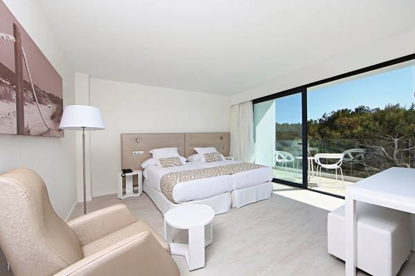 Innenansicht eines Doppelzimmers im Iberostar Cala Millor Hotel mit Bett, Sessel, Tisch und Balkon.