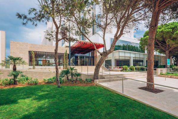 Außenansicht des Iberostar Cala Millor Hotels mit modernem Design, roten Dächern und umliegenden Bäumen