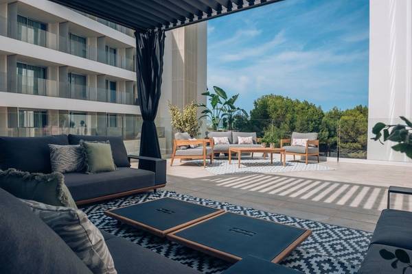 Außenbereich des Iberostar Cala Millor Hotels mit Möbeln und Ausblick auf Bäume und Gebäude