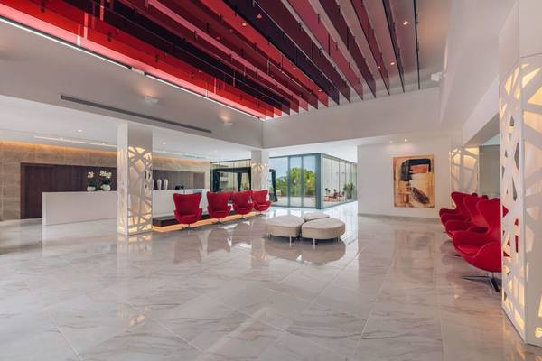Hotellobby des Iberostar Cala Millor mit roter Decke, weißen Fliesen und roten Stühlen.