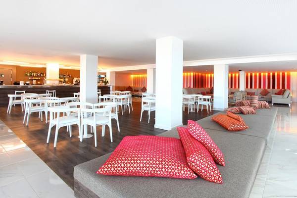 Loungebereich des Iberostar Cala Millor Hotels mit weißen Tischen und Stühlen sowie roten Kissen.