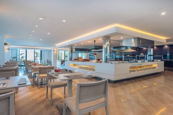 Innenansicht des Restaurants im Iberostar Cala Millor Hotel mit modernen Möbeln und einer großen Essenstheke.