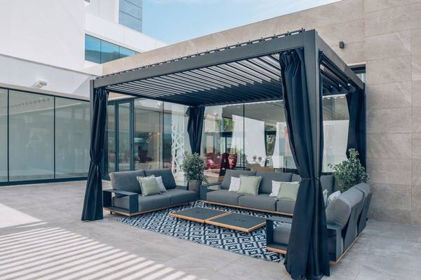 Außenlounge im Iberostar Cala Millor Hotel mit modernen Möbeln und schwarzen Vorhängen.