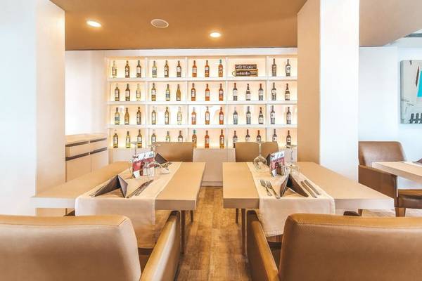 Interieur des Marins Playa Suites Hotels mit geräumigen Esstischen, Holzboden und einer Wand mit Alkoholflaschen.