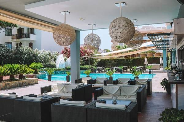 Loungebereich im Freien des Marins Playa Suites Hotels mit Sofas und einem Pool im Hintergrund.