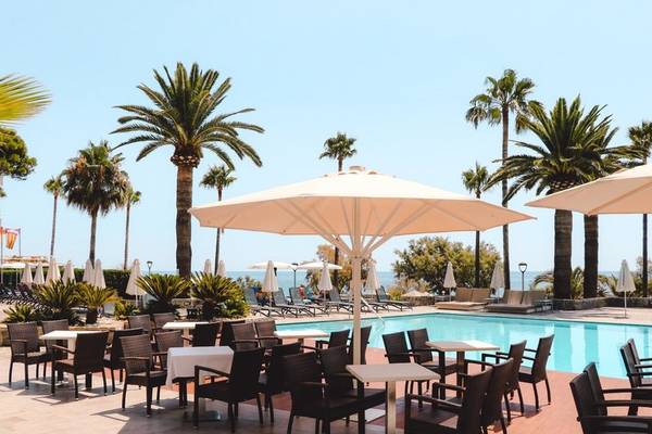 Außenbereich des Marins Playa Suites Hotels mit Pool, Tischen und Sonnenschirmen.
