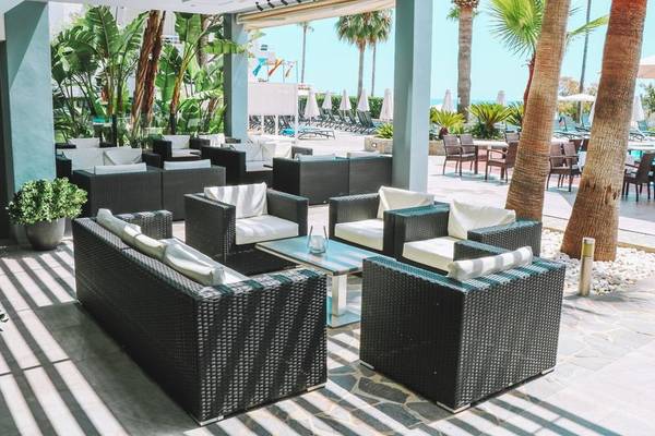 Außenbereich des Marins Playa Suites Hotels mit Möbeln und Palmen.