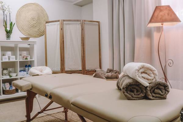 Massageraum im Marins Playa Suites Hotel mit Behandlungsbetten, Handtüchern und einer Lampe.