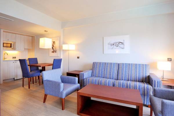 Wohnzimmer der Marins Playa Suites mit blauen Möbeln, einem Sofa, einem Tisch und Stühlen.