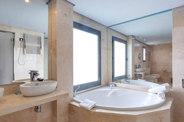 Badezimmer im Marins Playa Suites Hotel mit Badewanne, Spiegel und Waschbecken.