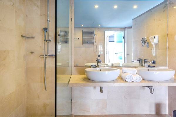 Badezimmer im Marins Playa Suites Hotel mit zwei Waschbecken, Spiegel und Dusche.