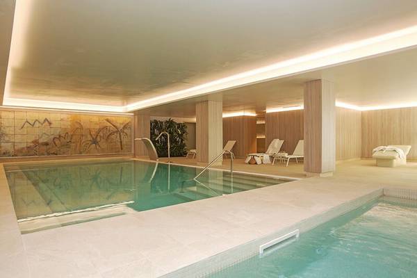 Innenpool im Sabina Playa Hotel mit zwei Becken, Liegen und Wanddekoration.