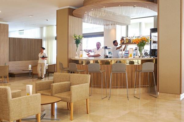 Rezeption im Sabina Playa Hotel mit Bar, Stühlen und Blumen.