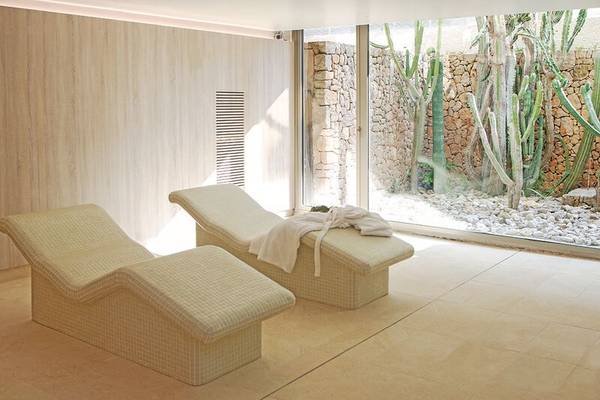 Wellness-Bereich im Sabina Playa Hotel mit zwei Liegen und Blick auf Kakteen.
