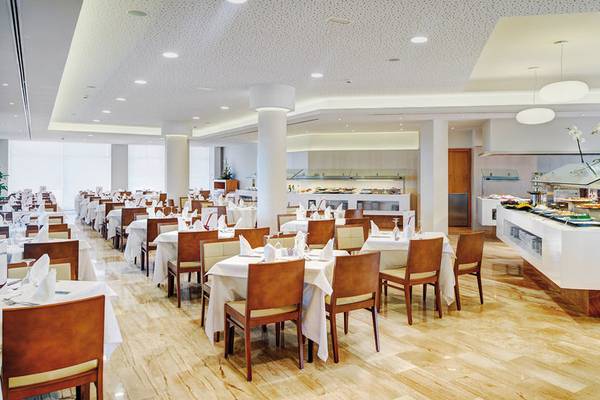 Restaurant im Hipotels Dunas Cala Millor mit gedeckten Tischen und Buffet.