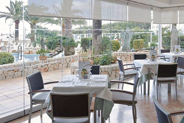 Restaurant im Hipotels Dunas Cala Millor mit großen Glaswänden und Blick auf den Pool.