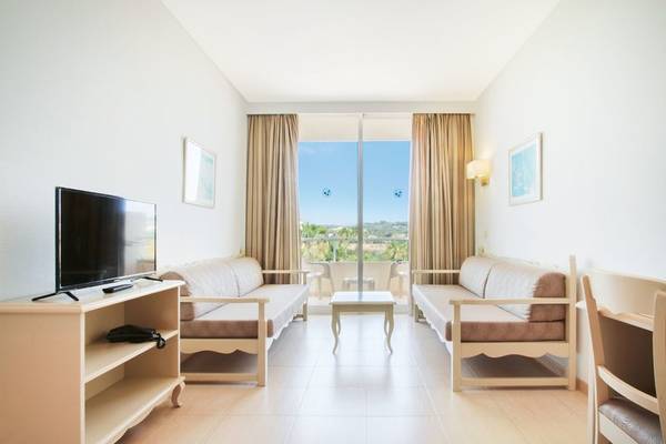 Wohnzimmer im Bakour Garbi Cala Millor Hotel mit zwei Sofas, Fernseher und Tisch.