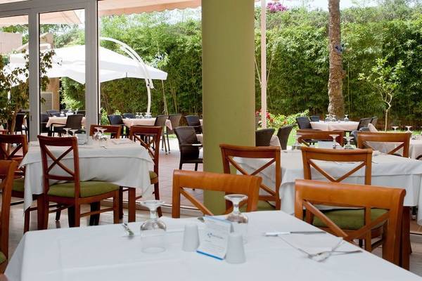 Gartenrestaurant im Bakour Garbi Cala Millor Hotel mit Tischen und Stühlen unter weißen Sonnenschirmen.