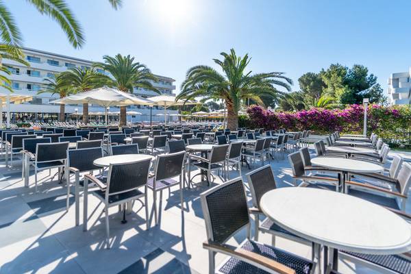 Außenterrasse des Millor Sol Hotels mit vielen Tischen und Stühlen, Palmen und Sonnenschirmen.