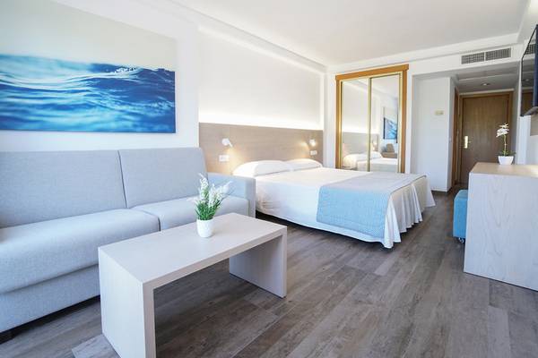 Hotelzimmer im Millor Sol mit Bett, Sofa, Tisch, Fernseher und Gemälde.