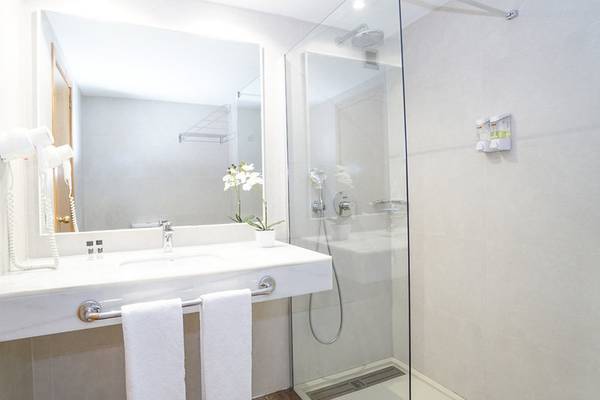 Ein Badezimmer mit einer Glasdusche, einem Spiegel und einem Waschbecken mit Handt üchern.