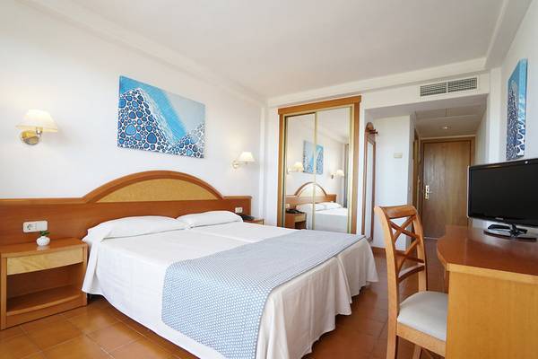 Doppelzimmer im Hotel Millor Sol mit zwei Betten, Schreibtisch, Fernseher und offenem Badezimmerspiegel.
