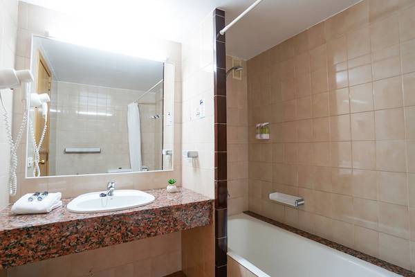 Badezimmer im Millor Sol Hotel mit Waschbecken, Spiegel und Badewanne.