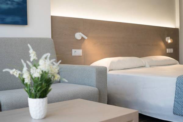 Schlafzimmer im Millor Sol Hotel mit Bett, Sofa und Nachttisch.