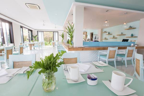 Innenansicht des Restaurants im TIA Wellness Resort mit blauen Tischen, Stühlen und einer Theke.