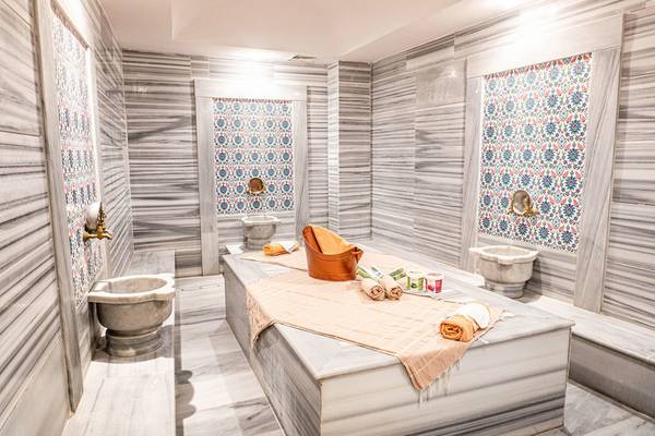 Innenraum des Green Nature Diamond Hamams mit Marmorwänden, dekorativen Fliesen, Badewanne und Handtüchern.