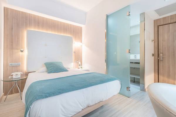 Ein modernes Hotelzimmer im Kyrat Amarac Hotel mit einem Doppelbett, einem Nachttisch und einer Dusche.