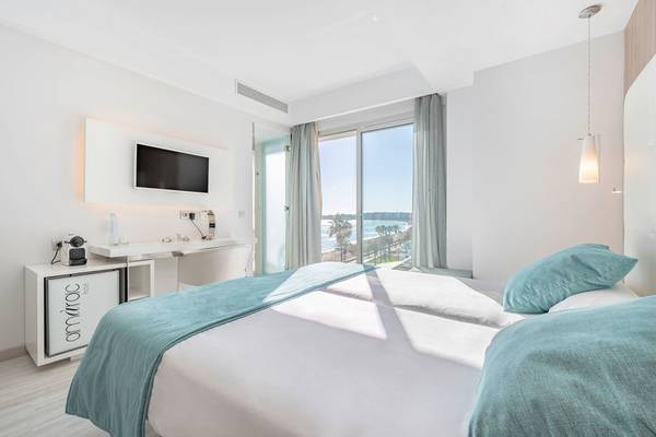 Doppelzimmer mit Meerblick im Kyrat Amarac Hotel mit einem großen Bett, Fernseher und Schreibtisch mit Blick auf den Strand.