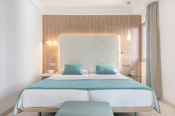 Bett im Zimmer des Kyrat Amarac Hotels, mit blauen Kissen und weißer Bettwäsche.